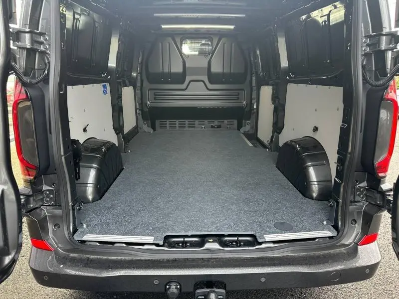 Vue arrière du Volkswagen Transporter Procab gris 2025, montrant l’espace de chargement avec cloison en L et plancher protégé.