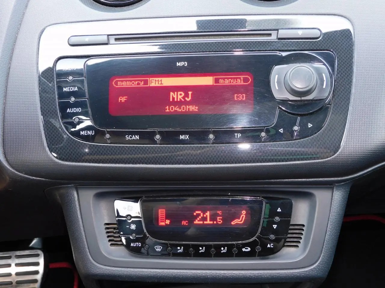 Tableau de bord de la SEAT Ibiza Cupra 2011 noir, affichage radio NRJ et climatisation automatique à 21,5°C.