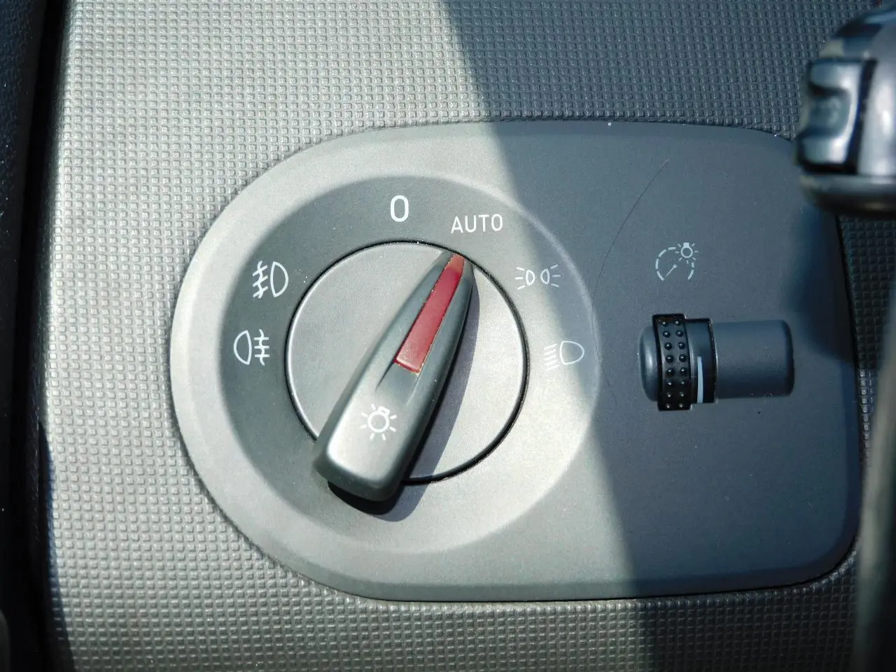 Gros plan sur le sélecteur d'éclairage intérieur gris du tableau de bord d'une SEAT Ibiza Cupra noire.