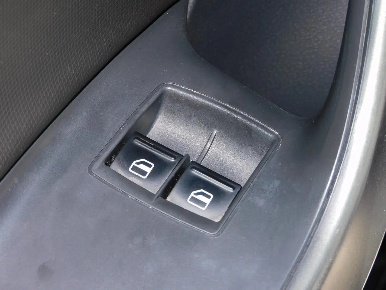 Gros plan sur les boutons de commande des vitres électriques côté conducteur d'une SEAT Ibiza Cupra noire.