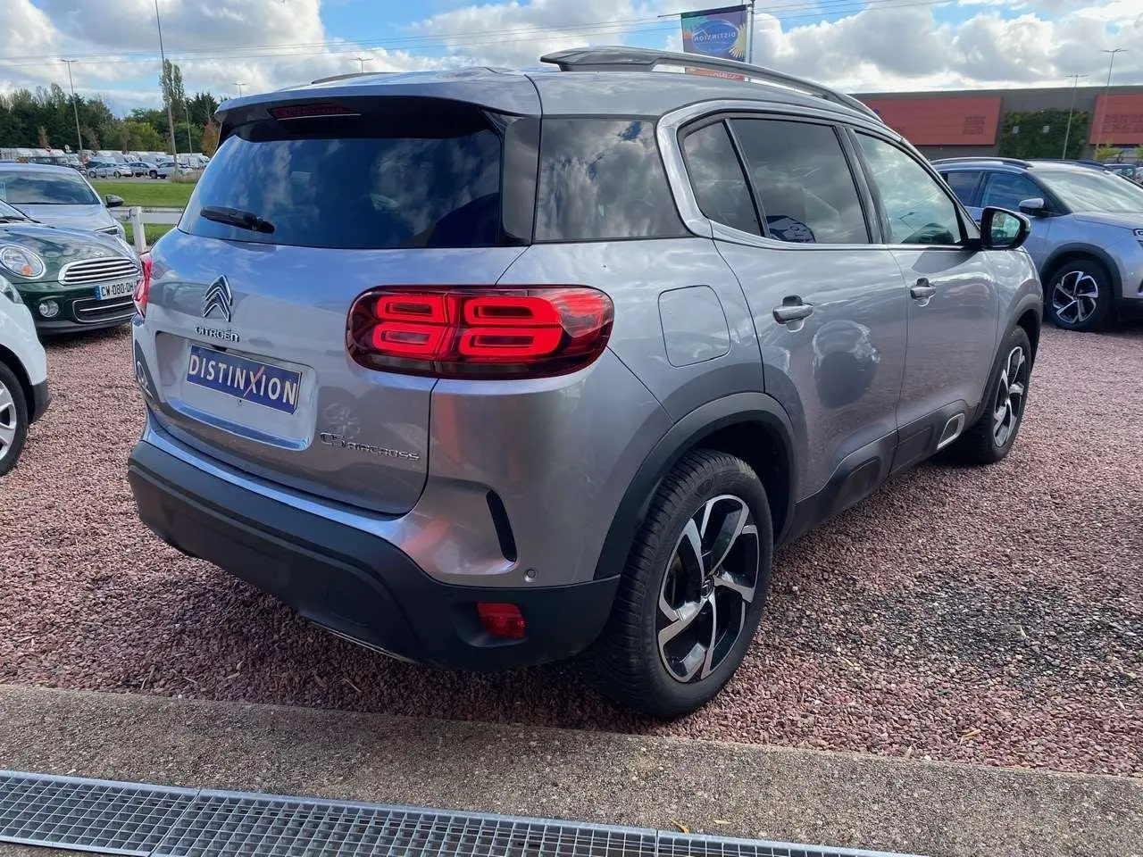 Vue 3/4 arrière droit d'un Citroën C5 Aircross gris Artense avec vitres surteintées et jantes bicolores.