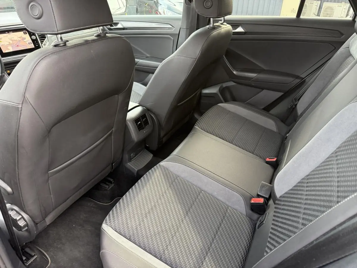 Vue intérieure arrière du Volkswagen T-Roc 1.5 TSI R-Line avec sièges en tissu gris et accoudoirs en simili-cuir noir.