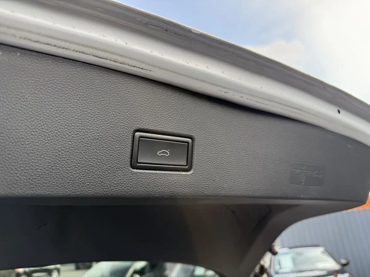 Bouton d'ouverture électrique du hayon sur le coffre d'un Volkswagen T-Roc gris, vue intérieure arrière.