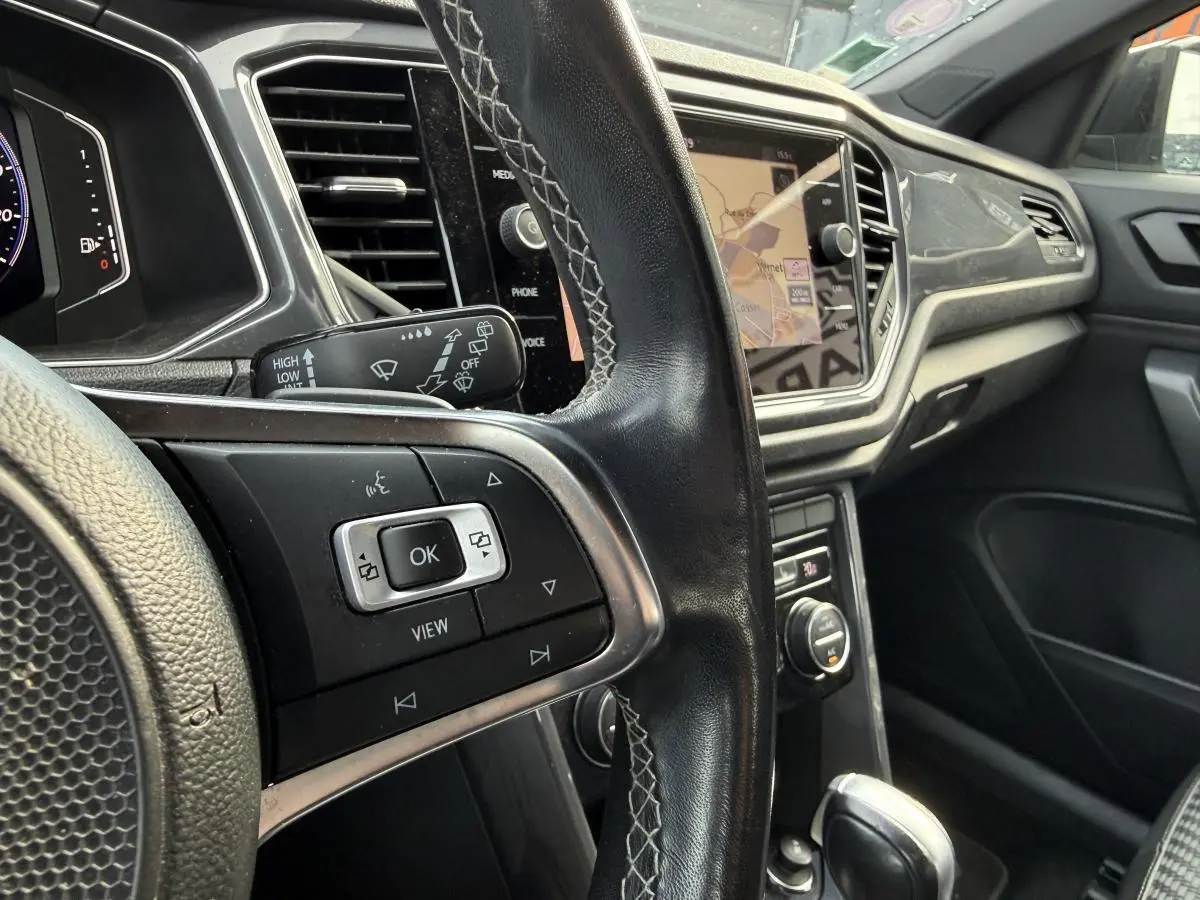 Vue intérieure rapprochée du volant en cuir noir et de la console centrale avec écran tactile du Volkswagen T-Roc R-Line 2020.