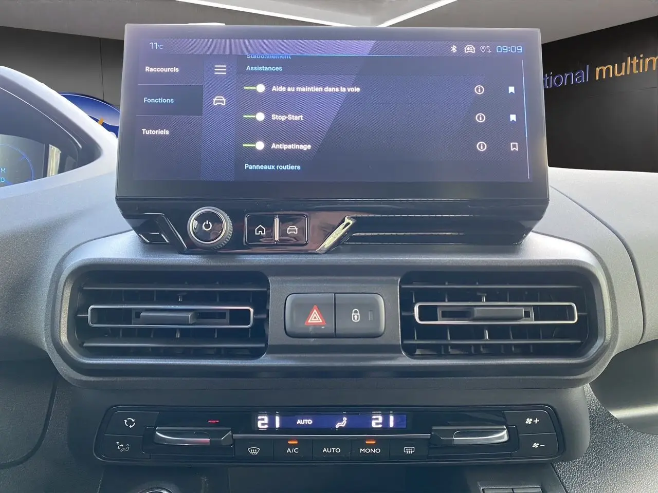 Vue rapprochée du tableau de bord du Peugeot Rifter 2025 avec écran tactile et commandes de climatisation.