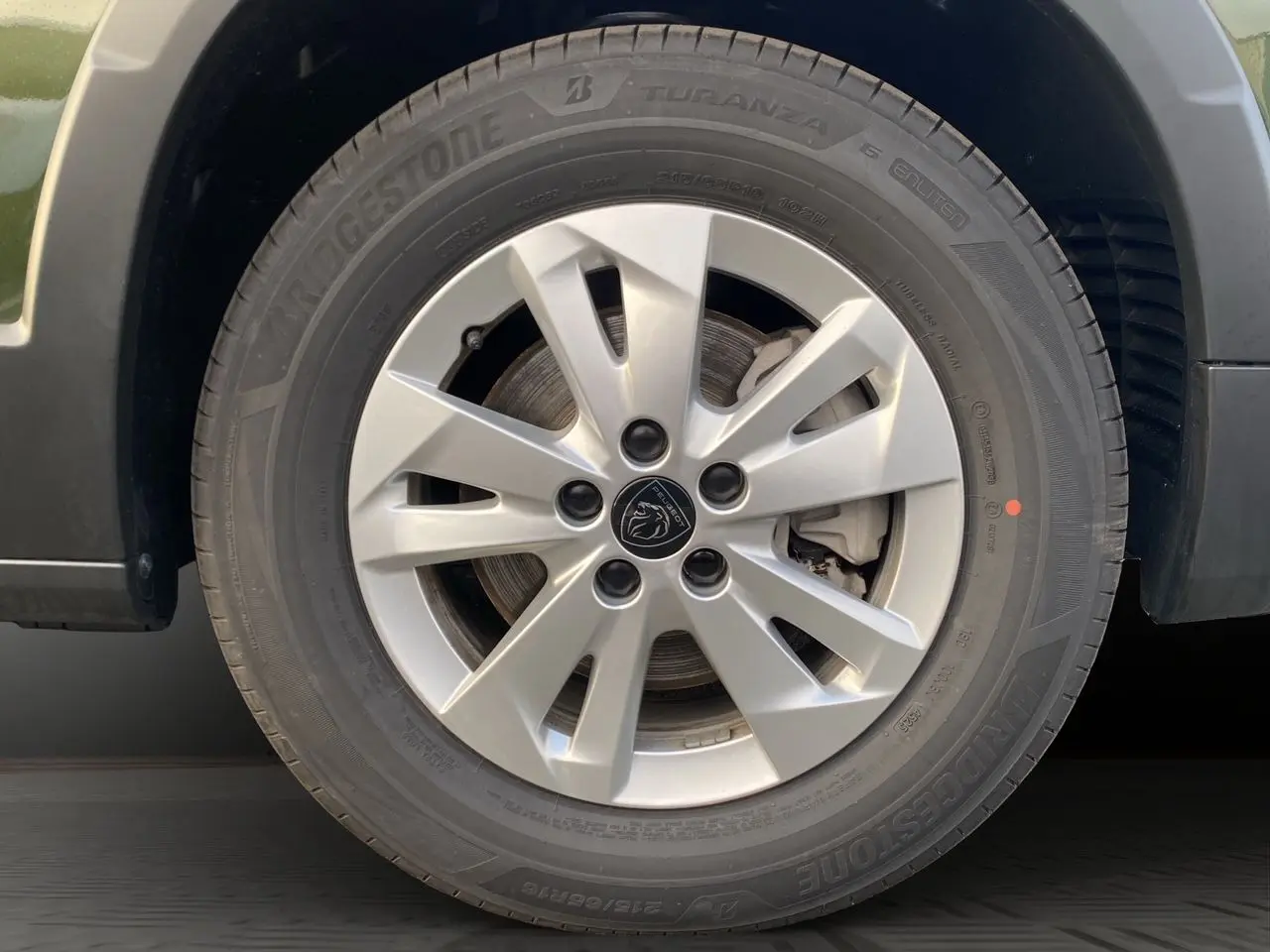 Gros plan sur la jante alliage 16 pouces Taranaki argentée du Peugeot Rifter vert Sirkka, avec logo lion au centre.