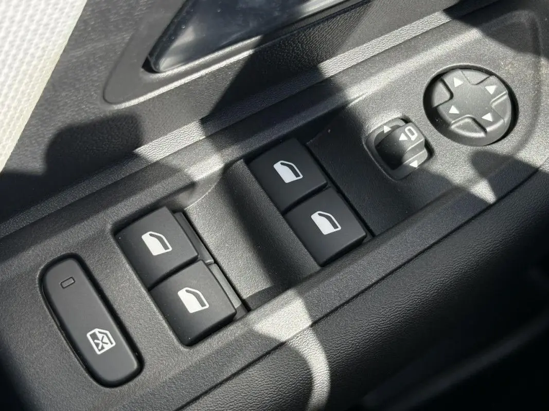 Gros plan sur les commandes de lève-vitres et réglages des rétroviseurs côté conducteur d'une Citroën C4 hybride 2025.