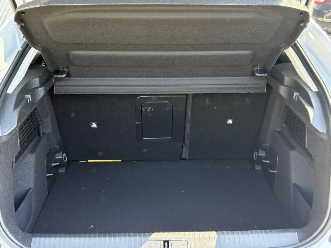 Coffre ouvert de la Citroën C4 Hybrid blanc Okenite, vue arrière montrant l’espace de chargement vide et la tablette arrière relevée.