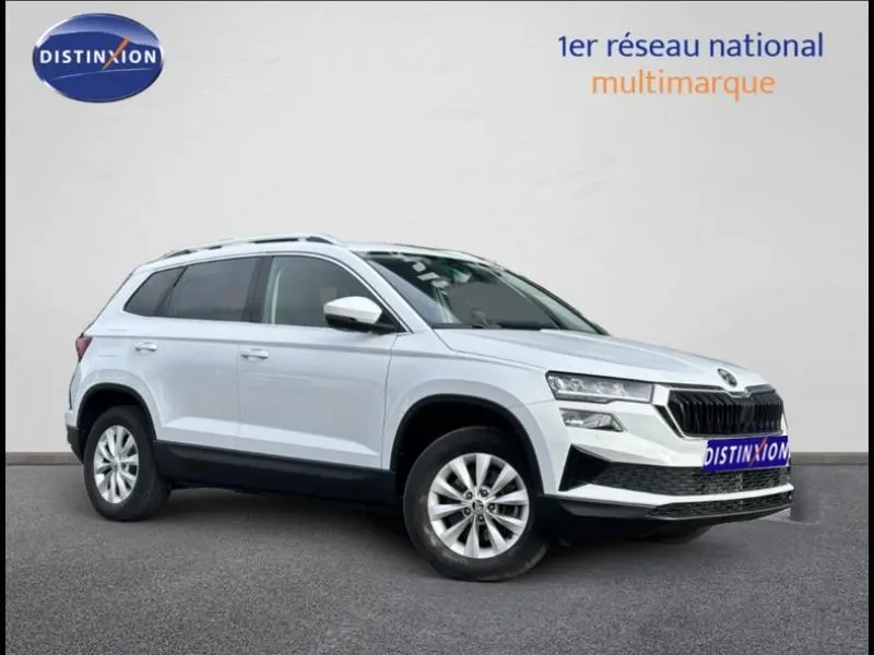 Vue 3/4 avant droite d'un SKODA KAROQ blanc lune métallisé avec calandre noire et jantes alliage.