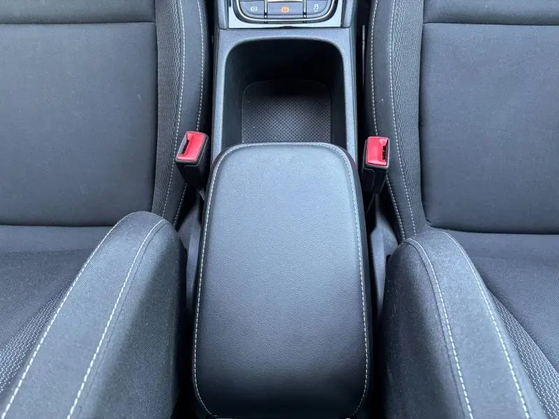 Vue plongeante sur l'accoudoir central noir et les sièges en tissu noir de la Skoda Karoq 2024.