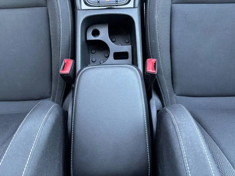 Vue plongeante sur l'accoudoir central noir et les sièges tissu noir du Skoda Karoq 2024 version diesel.