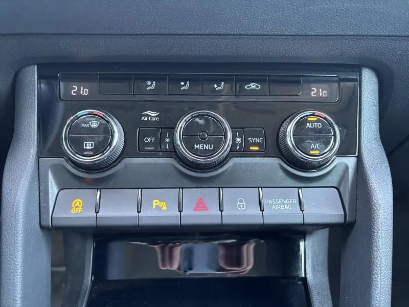 Vue rapprochée de la console centrale du Skoda Karoq 2024, avec commandes climatisation et boutons de sécurité noirs.