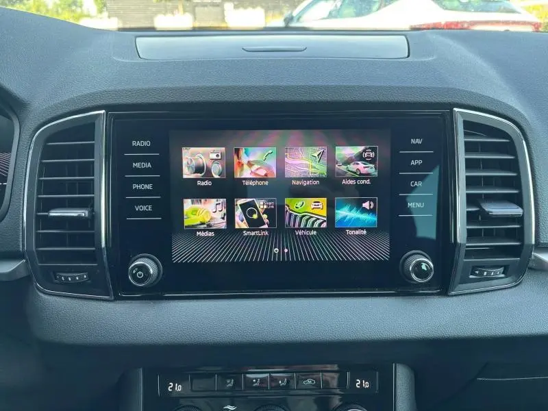 Écran tactile central du tableau de bord du Skoda Karoq blanc Lune, avec menus multimédia et navigation visibles.