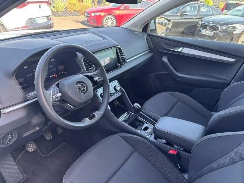Intérieur avant droit du Skoda Karoq 2024 avec volant cuir multifonction, écran tactile et sièges tissu noir.