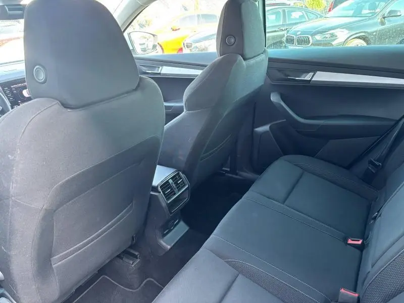 Vue intérieure arrière du Skoda Karoq 2024 avec sièges tissu noir et console centrale avec aérateurs arrière.