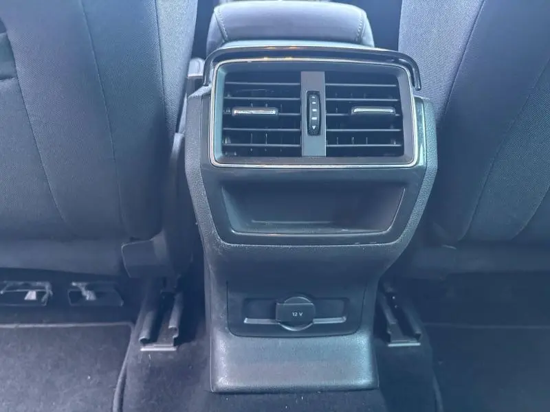 Gros plan sur la console centrale arrière noire du Skoda Karoq 2024 avec bouches d’aération et prise 12V visible.