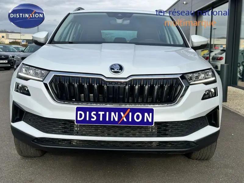 Vue frontale d'un Skoda Karoq blanc lune métallisée avec calandre noire et phares LED distinctifs.