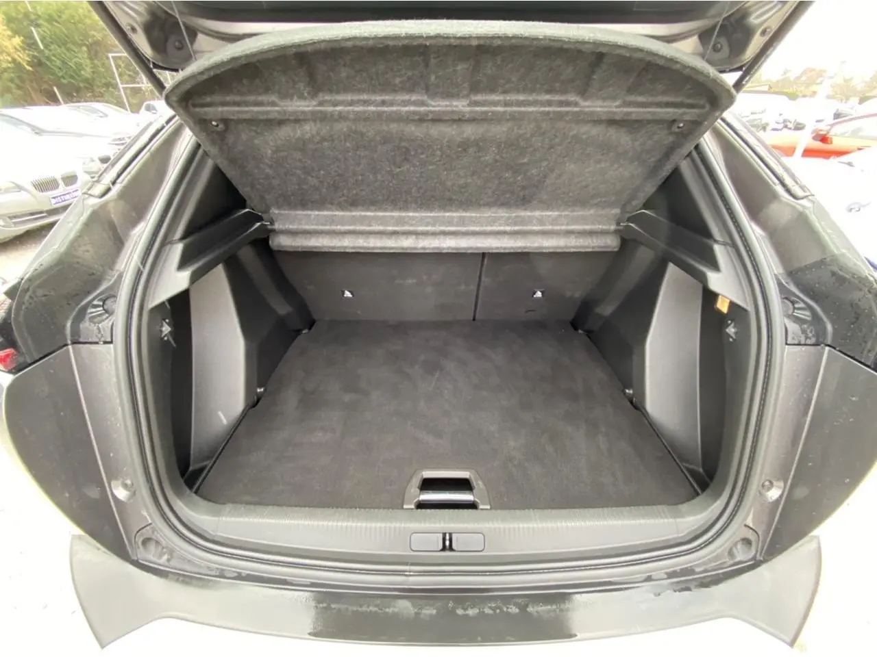 Coffre ouvert d'une Peugeot 2008 gris foncé vu de l'arrière, montrant un espace de chargement propre et spacieux.