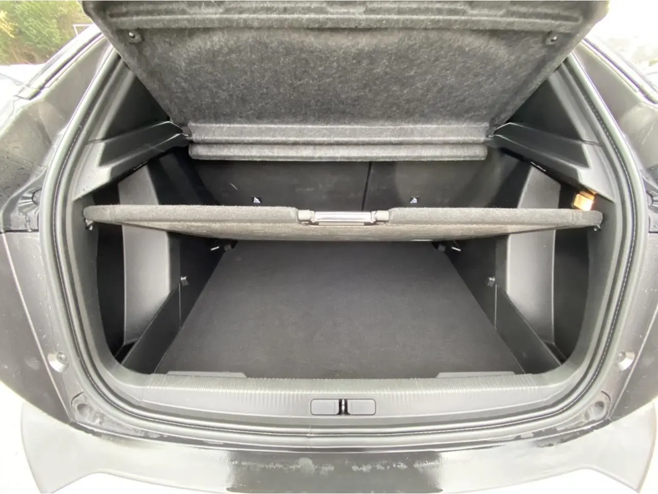 Coffre ouvert vu de l'arrière d'un Peugeot 2008 gris foncé, montrant l'espace de rangement et la tablette cache-bagages.