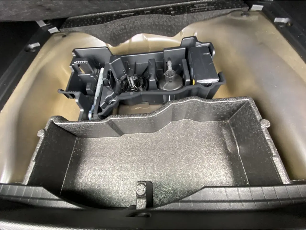 Coffre ouvert d'une Peugeot 2008 gris foncé, montrant le rangement sous plancher avec outils de bord.