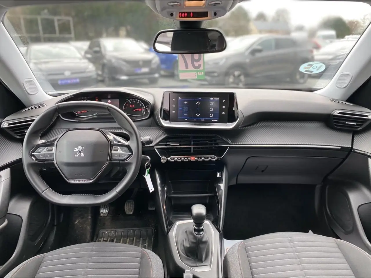 Vue intérieure avant du Peugeot 2008 2021 avec tableau de bord noir, volant compact et écran tactile central.