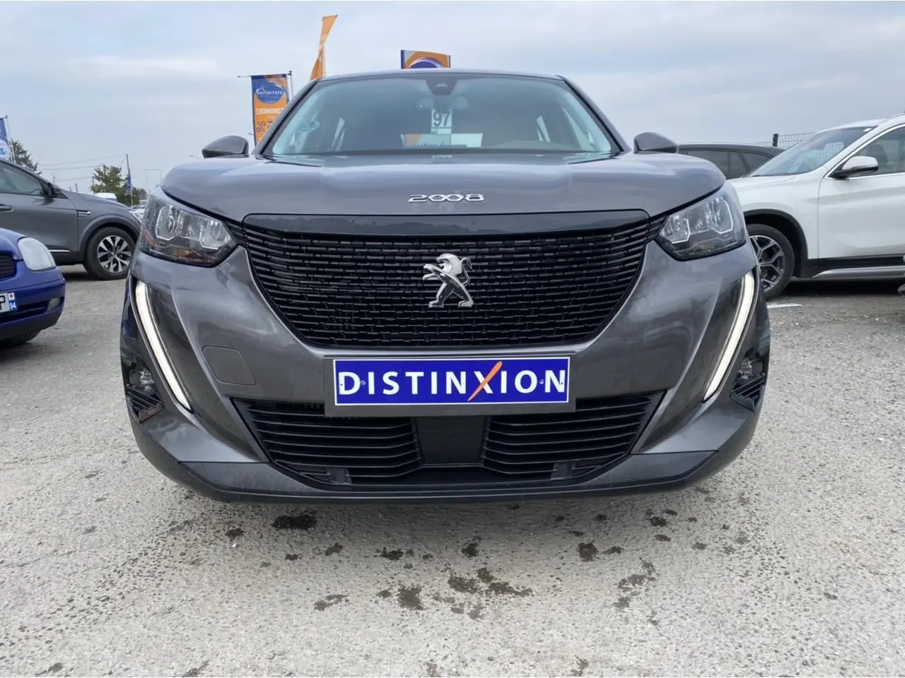 Vue frontale d'un Peugeot 2008 gris foncé avec calandre noire et feux diurnes LED en forme de griffes.