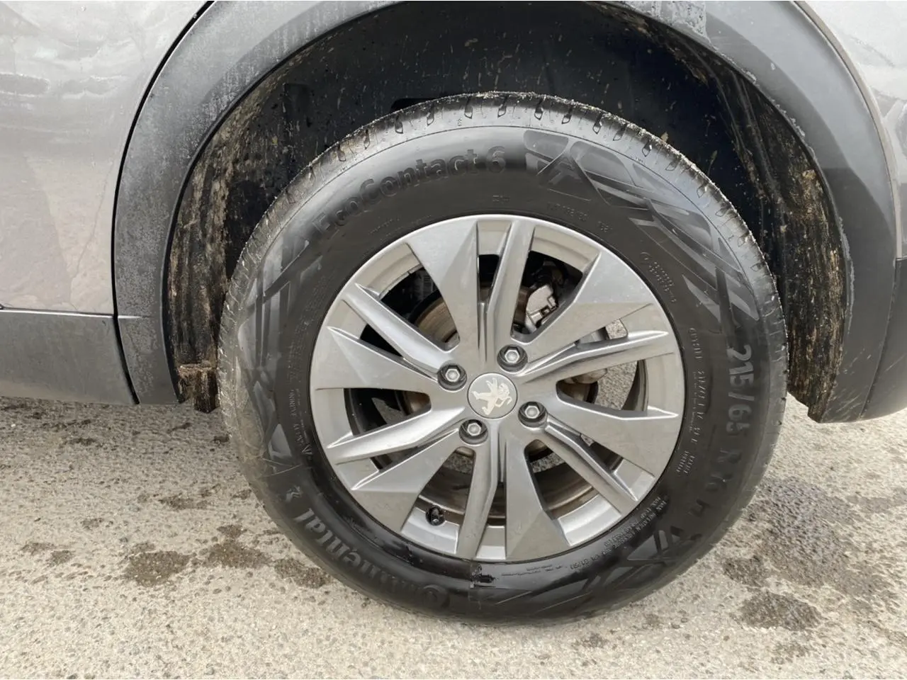 Gros plan sur la roue avant droite gris foncé d'un Peugeot 2008 2021 avec jante alliage et logo lion au centre.