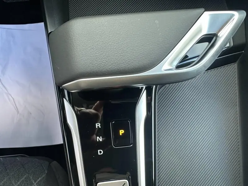 Gros plan sur la console centrale noire du MG ZS Hybrid+ 2025, montrant la commande de boîte auto avec mode parking activé.