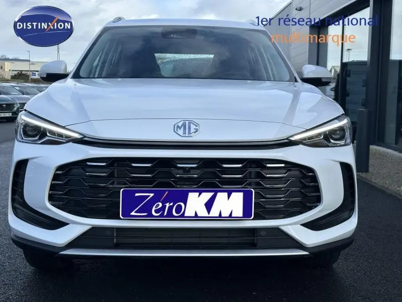 Vue frontale d'un MG ZS Hybrid+ blanc avec calandre noire et phares LED allumés.