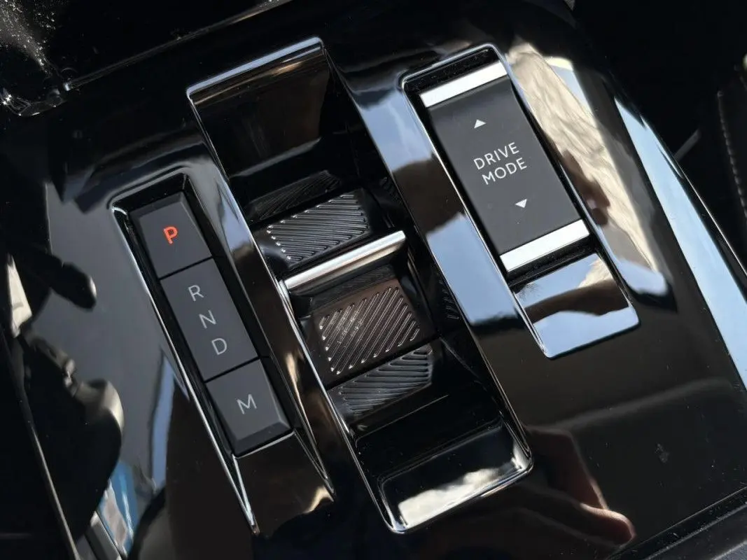 Gros plan sur la console centrale noire brillante de la Citroën C4 Hybrid 145 CH, avec sélecteur de vitesses automatique et bouton Drive Mode.