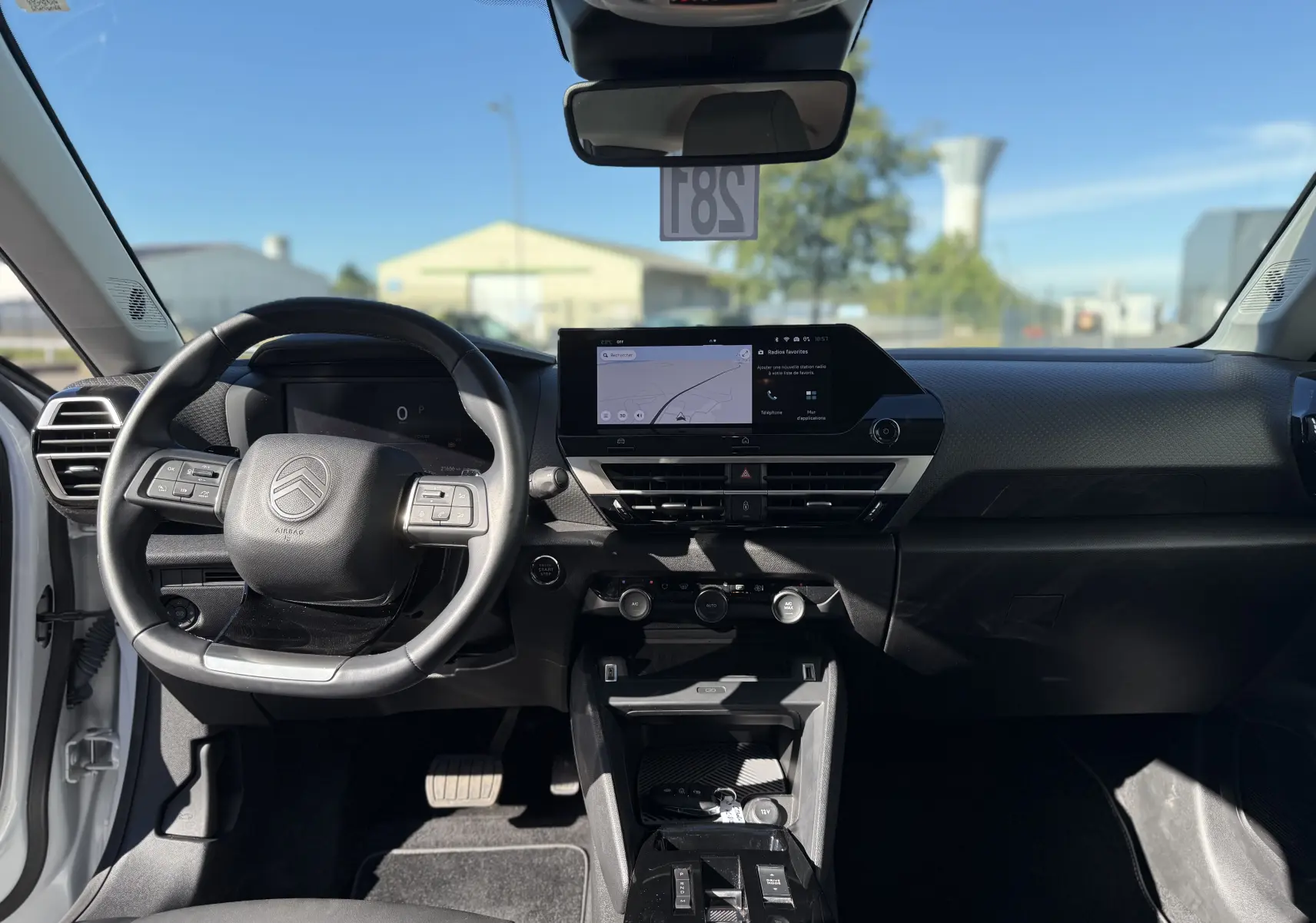 Vue intérieure frontale du tableau de bord noir de la Citroën C4 Hybrid 145 CH avec écran tactile et volant multifonction.