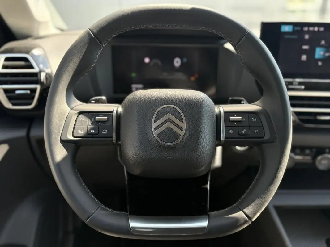 Vue rapprochée du volant en cuir noir avec commandes intégrées de la Citroën C4 Hybrid 2025.