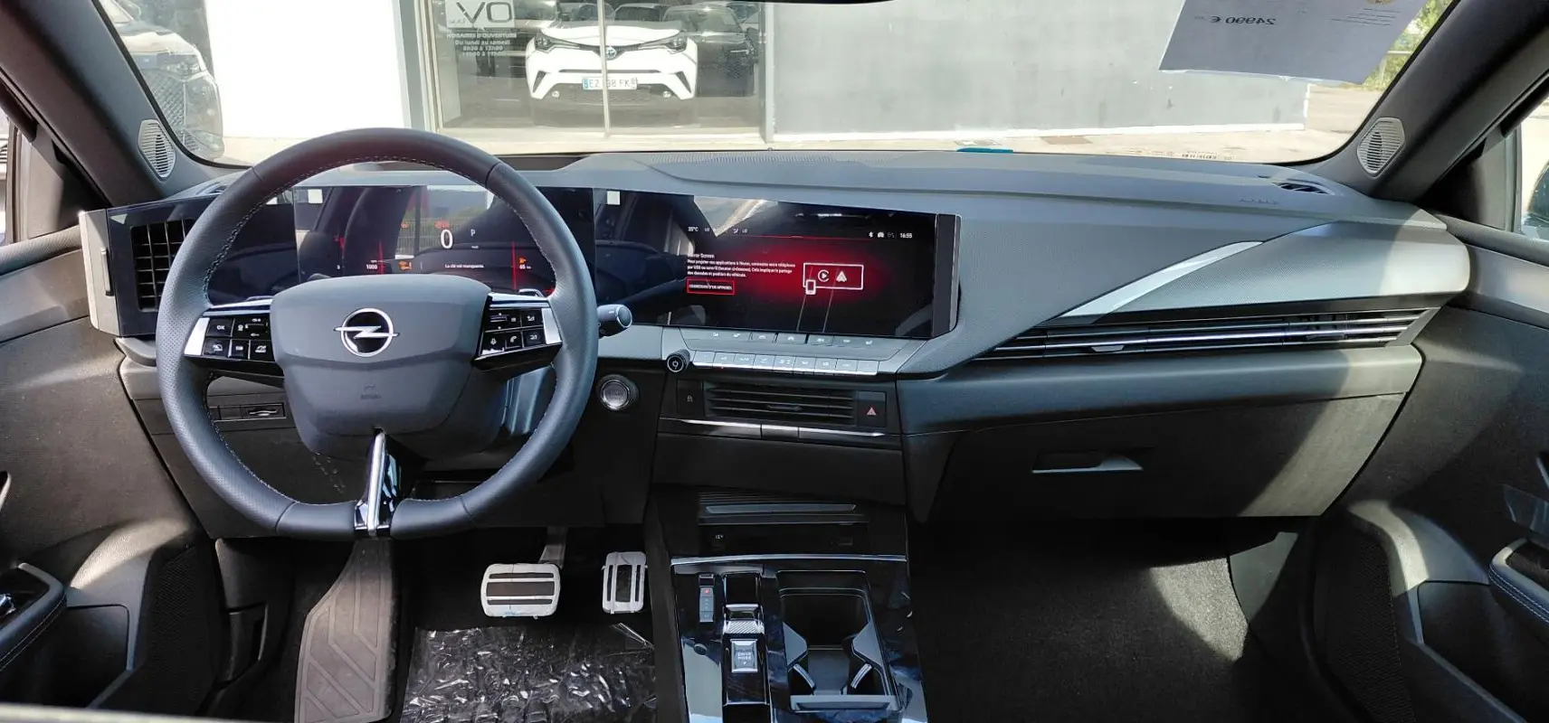Vue intérieure frontale de l’Opel Astra 2025 noire, avec tableau de bord numérique et volant cuir multifonction.