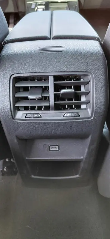 Vue rapprochée de la console centrale arrière noire de l'Opel Astra 2025, avec ventilation et port USB visibles.