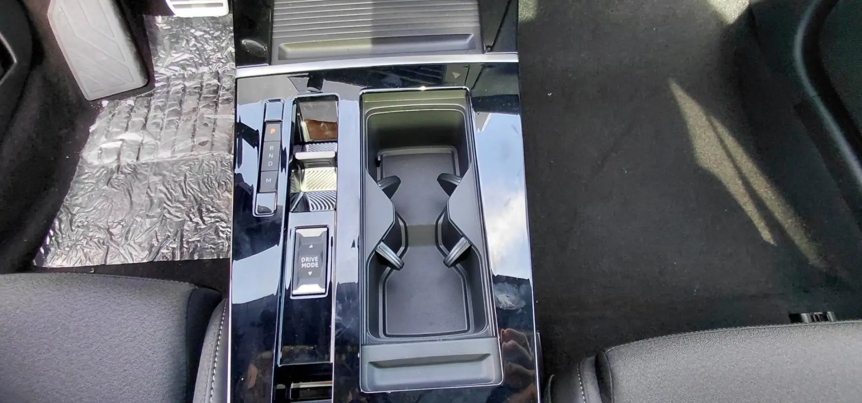 Vue plongeante sur la console centrale noire brillante de l’Opel Astra 2025 avec sélecteur de mode de conduite et porte-gobelets.