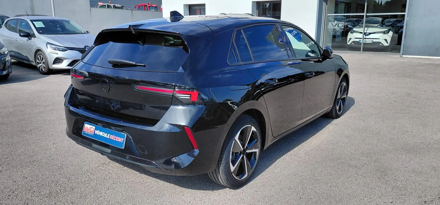 Opel Astra noire vue 3/4 arrière droit, jantes alliage 17 pouces et vitres surteintées en extérieur.