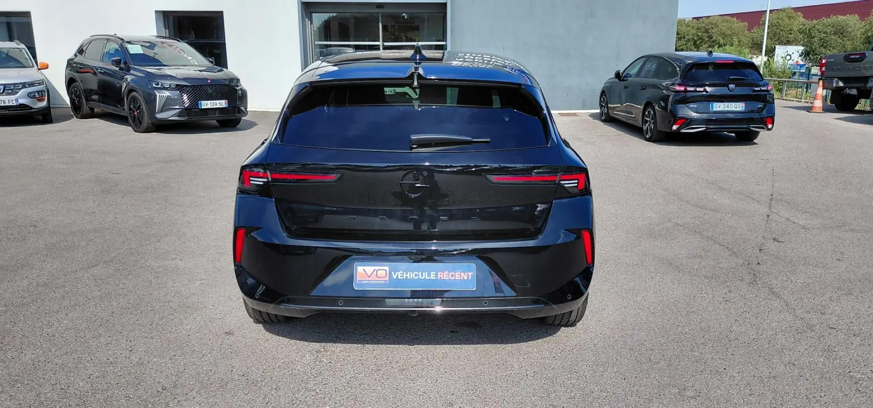 Vue arrière d'une Opel Astra noire 2025 avec feux LED fins et vitres surteintées, stationnée en extérieur.
