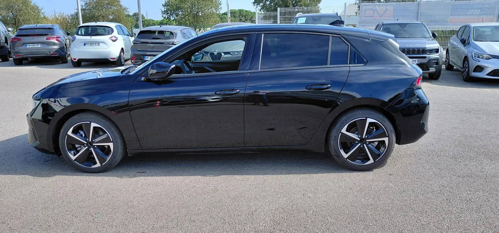 Opel Astra noire vue de profil côté gauche, avec vitres surteintées et jantes alliage 17 pouces.