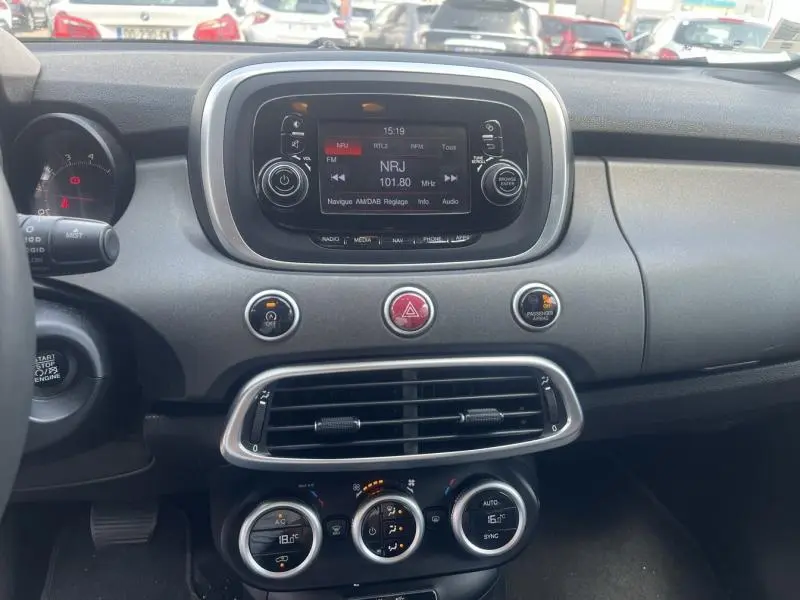 Tableau de bord de Fiat 500X 2015 avec écran tactile, commandes circulaires de climatisation et finition noire mate.