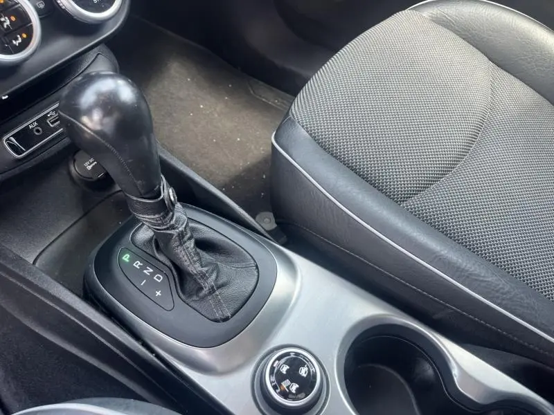 Gros plan sur la console centrale et levier de vitesse automatique noir, siège conducteur en tissu gris foncé du Fiat 500X 2015.