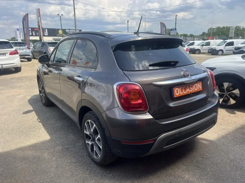Vue 3/4 arrière droite d'une Fiat 500X bronze métallisé avec jantes alliage et vitres surteintées en extérieur.