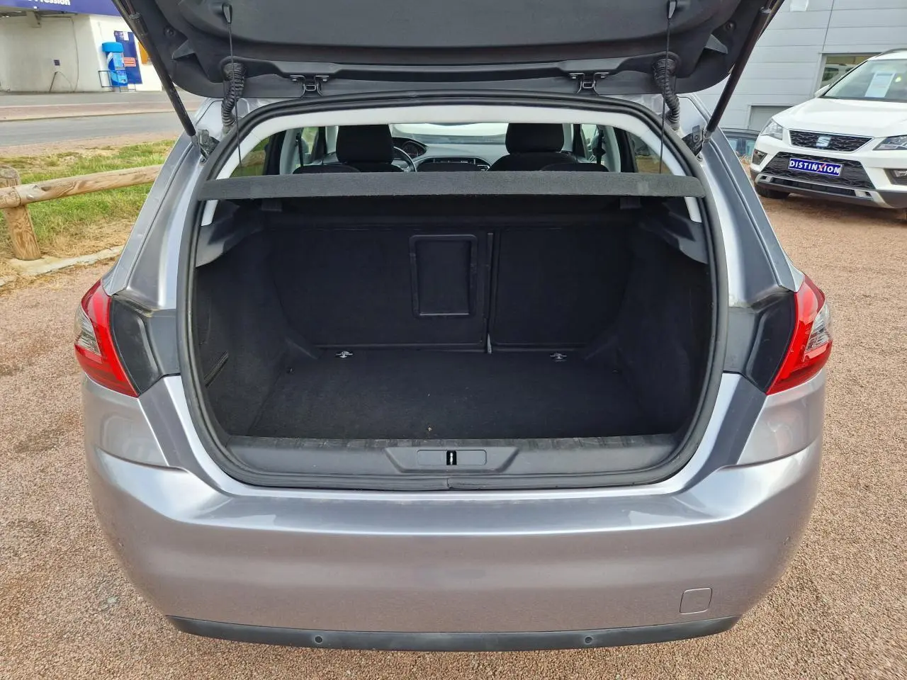 Coffre ouvert d'une Peugeot 308 gris artense vue de l'arrière, montrant un espace de chargement vide et propre.