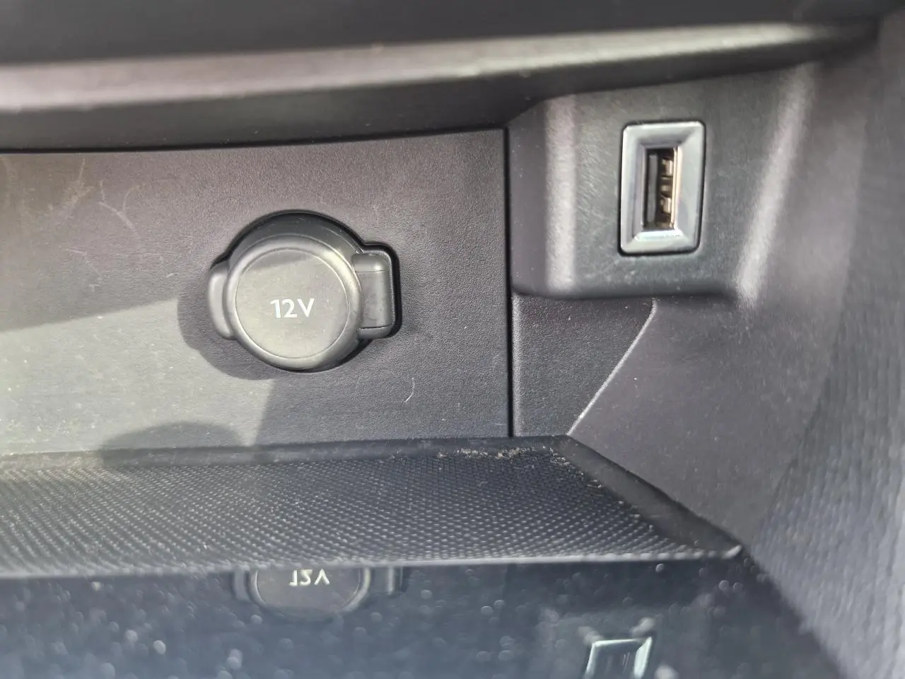 Prise 12V et port USB en gros plan sur la console centrale intérieure d'une Peugeot 308 gris artense de 2018