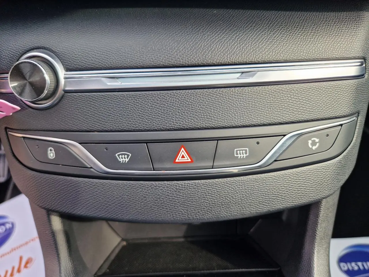 Gros plan sur la console centrale noire de la Peugeot 308 gris artense, avec boutons de verrouillage et alerte triangle rouge.