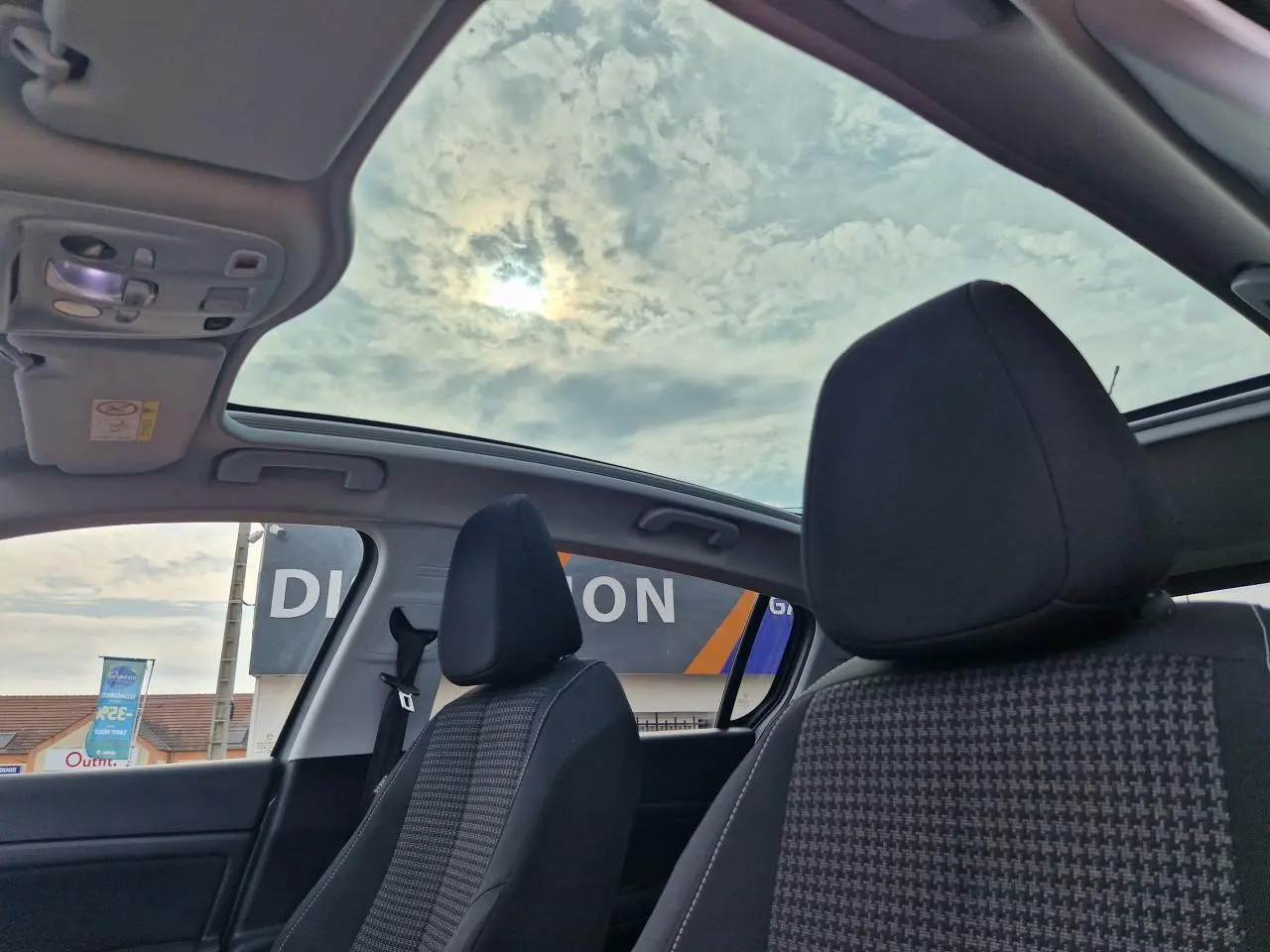 Intérieur de la Peugeot 308 2018 avec toit panoramique en verre et sièges avant en tissu noir à motifs.