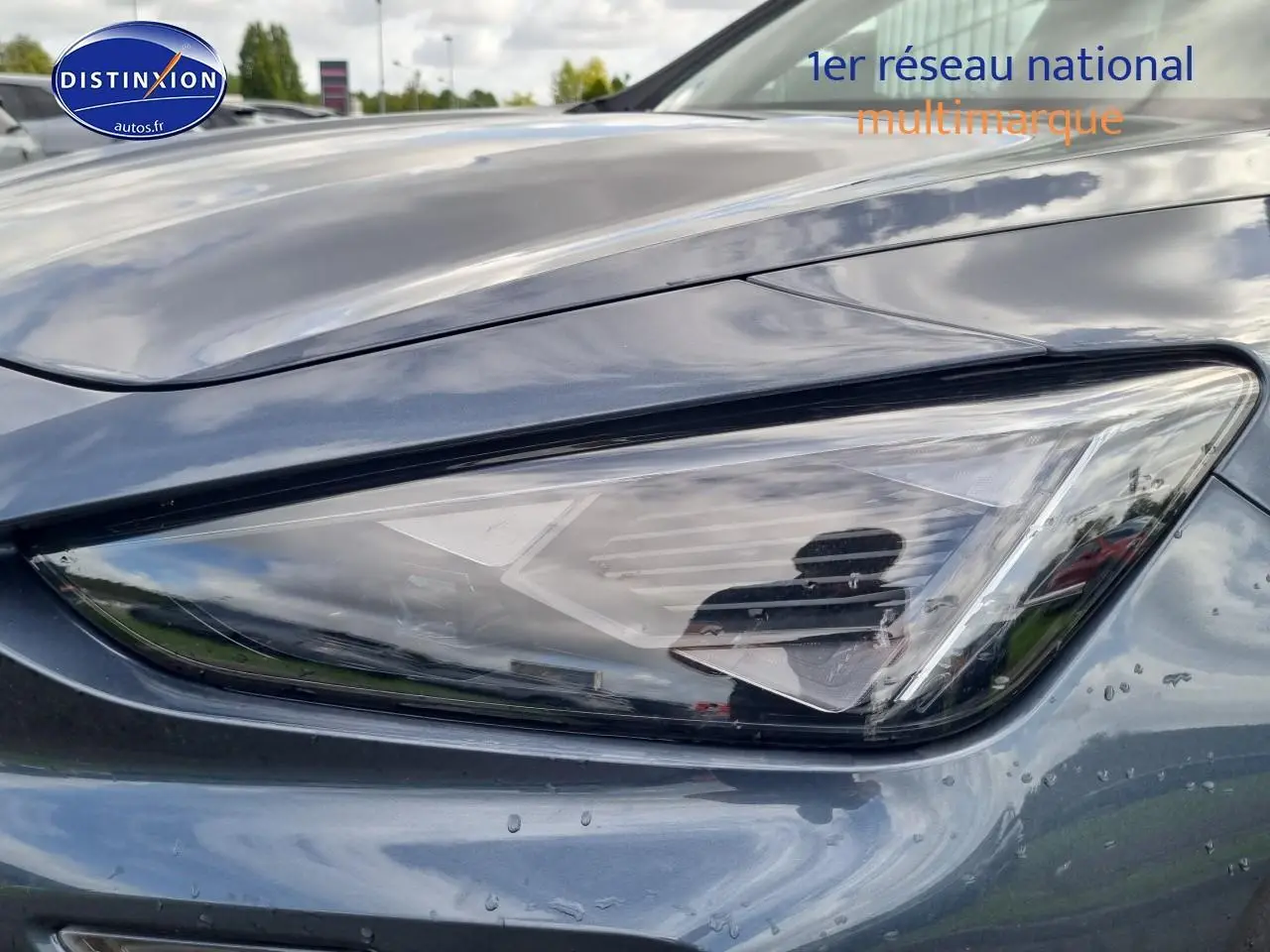 Gros plan sur le phare avant droit du CUPRA Formentor 2025 en gris magnétique avec reflets et gouttes d'eau visibles.