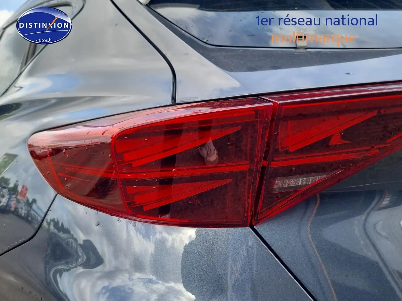 Gros plan sur le feu arrière droit du CUPRA Formentor gris magnétique 2025 avec reflets du ciel sur la carrosserie.