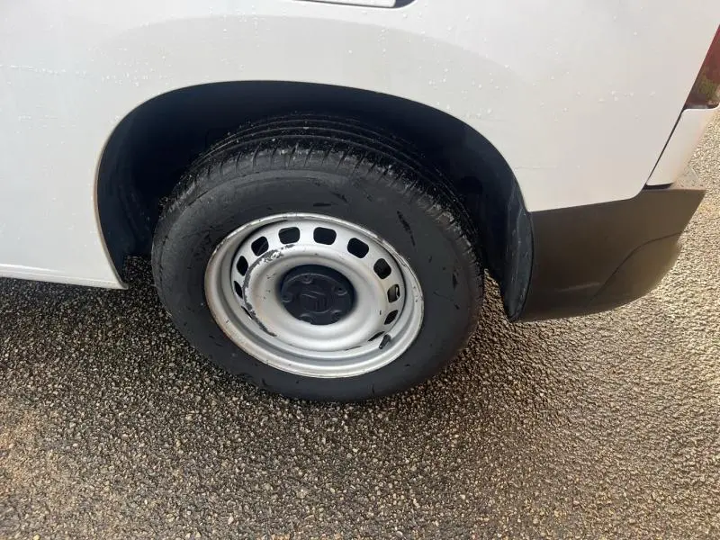 Gros plan sur la roue arrière droite du Citroën Berlingo Fourgon blanc Banquise avec jante acier et pare-chocs noir.