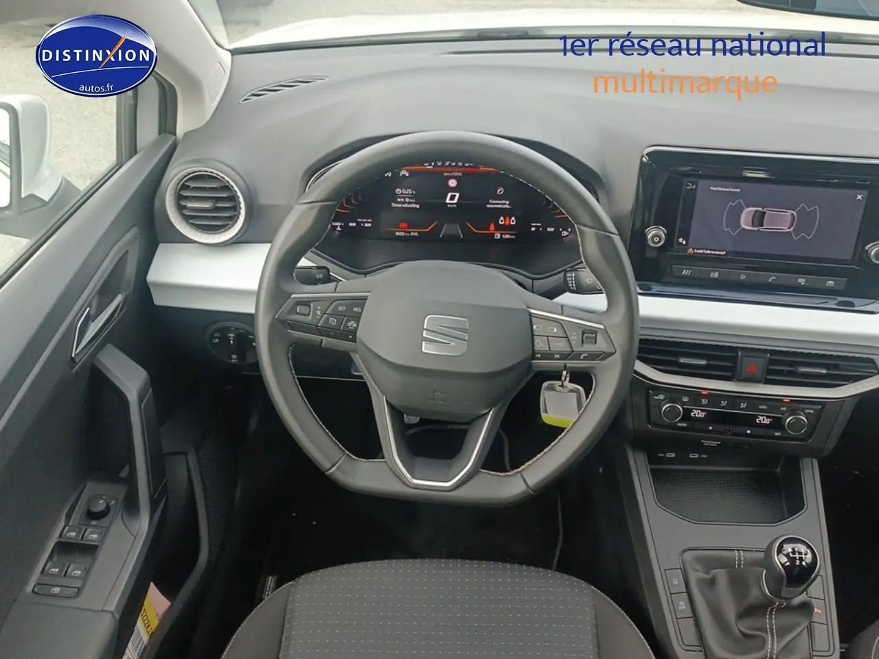 Vue intérieure centrée sur le volant cuir méplat et tableau de bord numérique de la SEAT Ibiza blanche Nevada 2025.