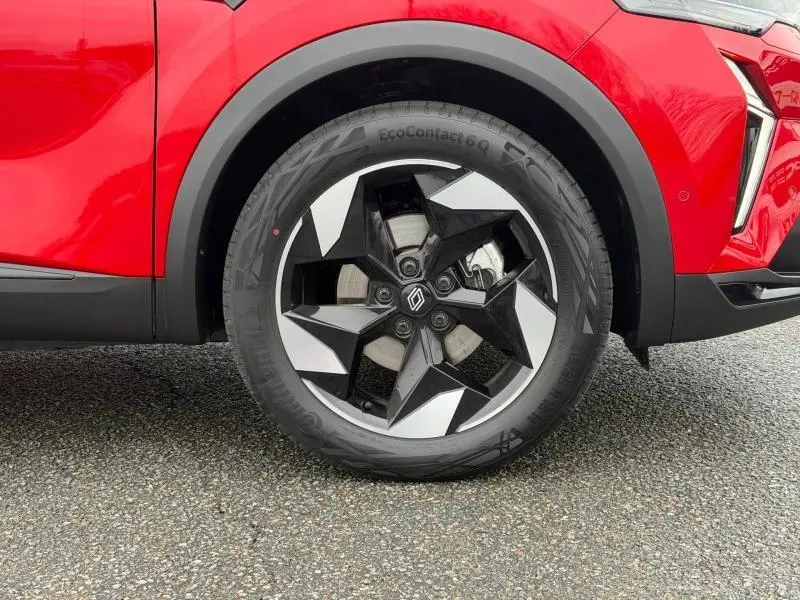 Gros plan sur la roue avant droite du Renault Captur 2025 Rouge Flamme, mettant en valeur la jante noire et argentée au design moderne.